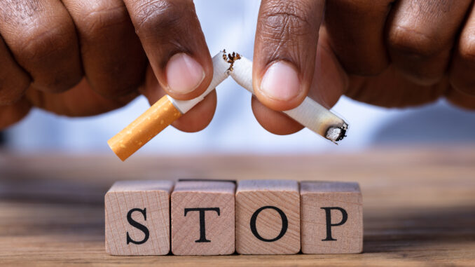 Man Breaking Cigarette Over Wooden Stop Blocks
